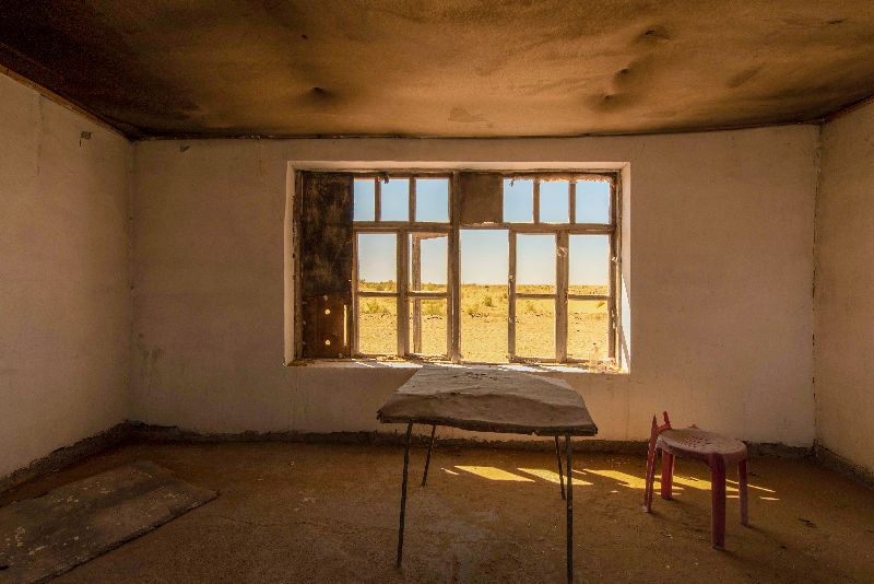 verlassene Hütte mit Hocker und Tisch mit Ausblick in die Wüste von Usbekistan
