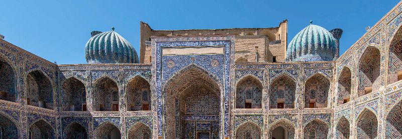 Innenhof der Medrese Tilya Kori in Samarkan mit reich verzierten Balkonnischen und türkisfarbenen Kuppeln rechts und links