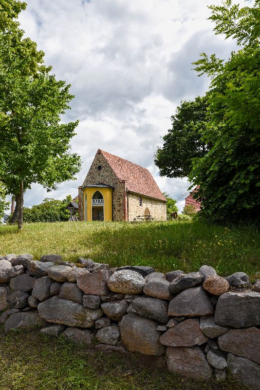 Hörspielkirche Federow mit Wiese und Steinmauer davor