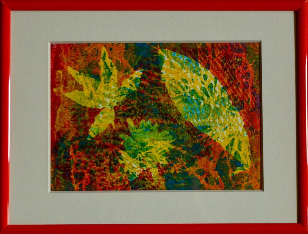 Bild mit Drucktechnik auf Gelatineplatte über getrocknete Blätter orange, gelb, rot, blaut, grün in orangem Rahmen