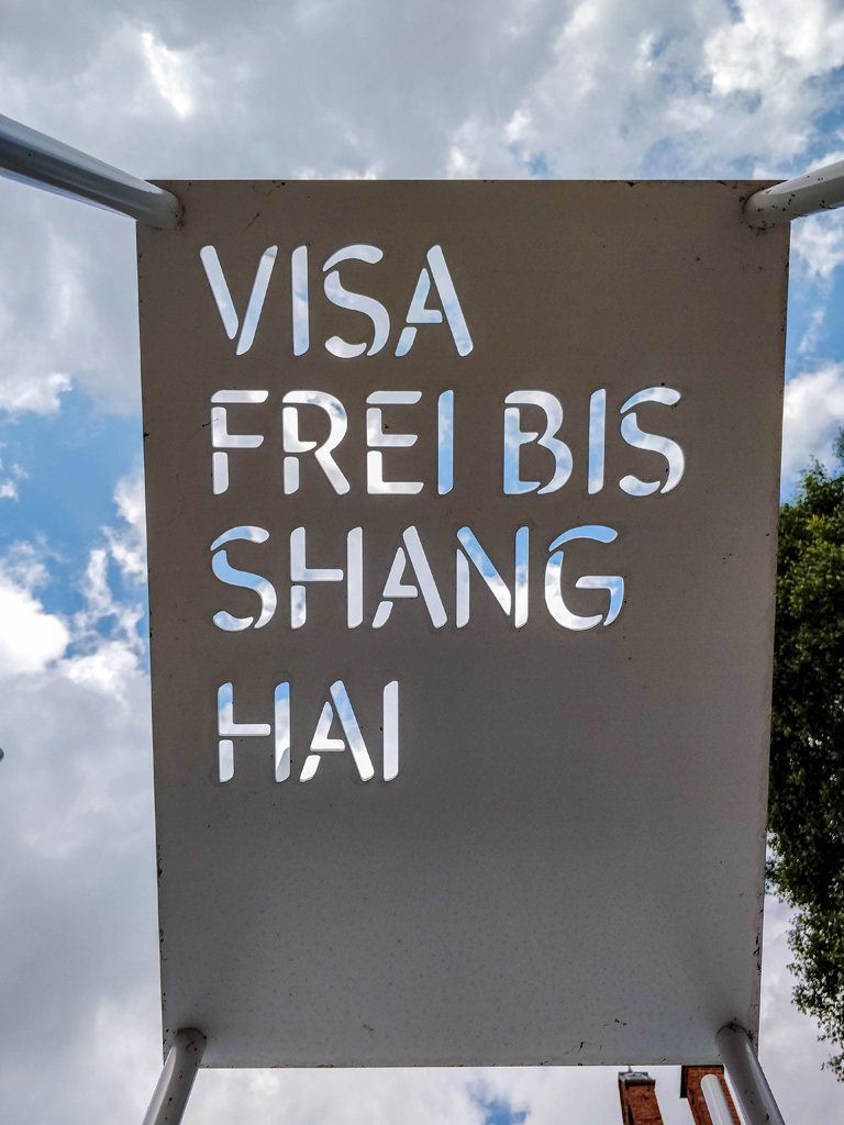 Schild mit Blick in den Himmel Visa Frei bis Shanghai - Gedenkinstallation in Waren an der Müritz