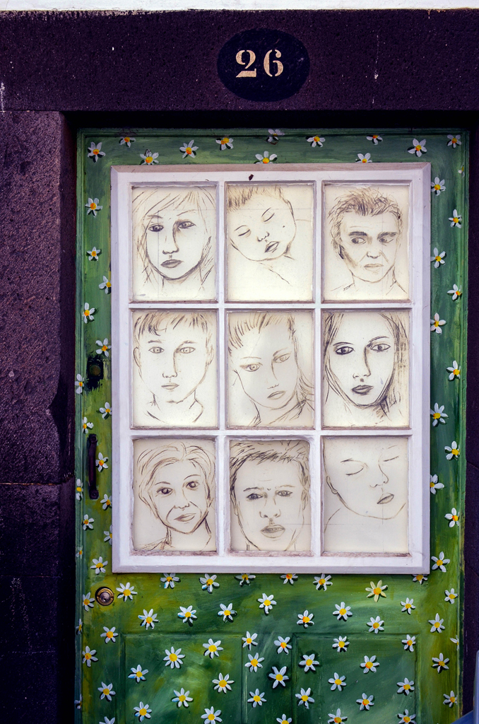 Kunstwerk Haustüre mit Gesichtern in Sprossenfenster gemalt auf grünem Hintergrund mit weißen Blümchen