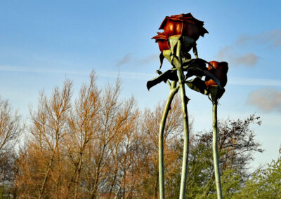 drei rote Rosen-Skulpturen aus Metall strecken sich in den Himmel von Irland