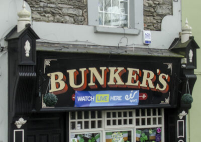 Bunkers Bar in County Kerry Irland. Sie hat eine schwarze Holzverkleidung und ist im weißen Gitterfenster mit St. Patrick Days Souvenirs geschmückt