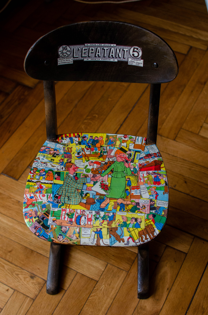 alter Grundschul-Stuhl in dunkelbraun mit alten französischen Comics von L´Epatant auf der Stuhlfläche