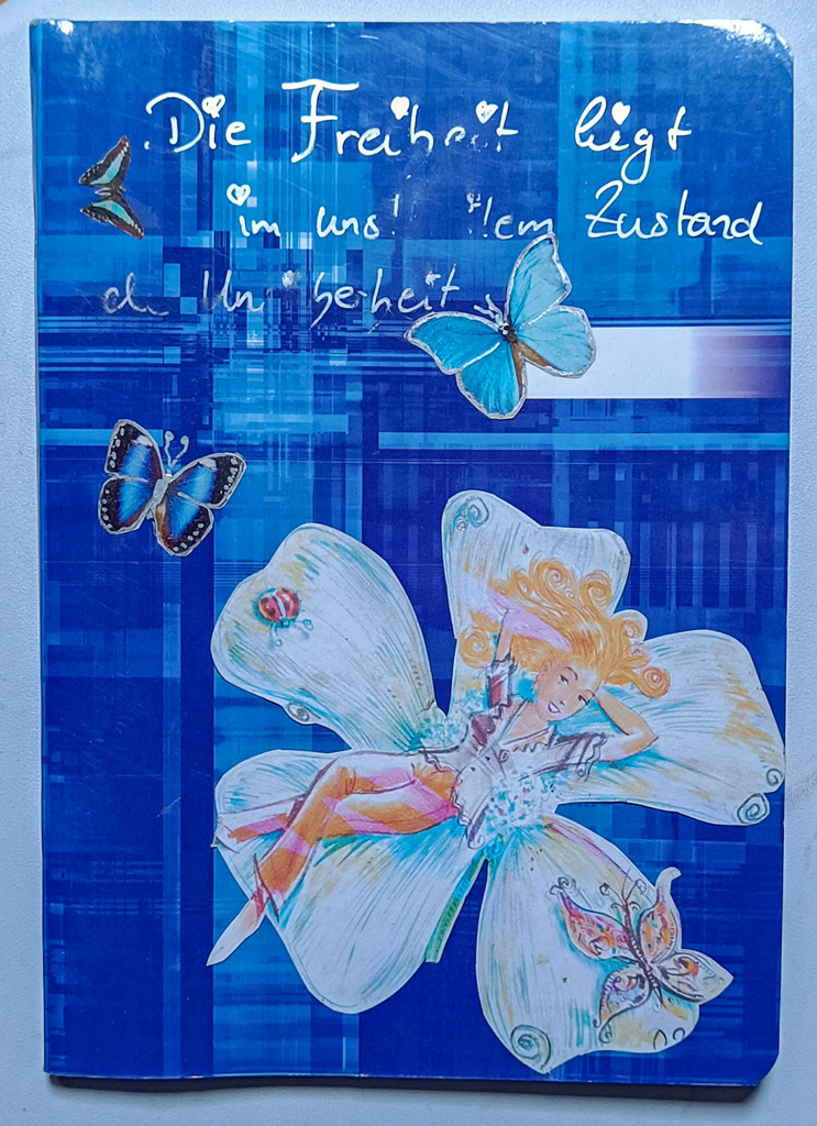 royalblaues Heft mit Papiercollage von Schmetterlingen, Frau liegend in einer großen weißen Blüte in Blautönen