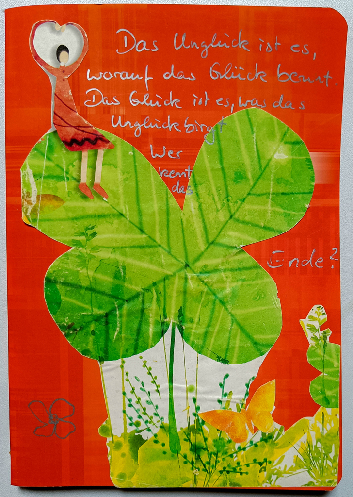 rotes Heft mit Papiercollage Frau auf grünem vierblättrigem Kleeblatt