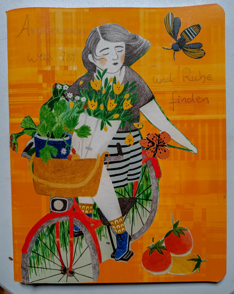 oranges Heft mit Papiercollage Frau auf Fahrrad mit Blumen im Korb