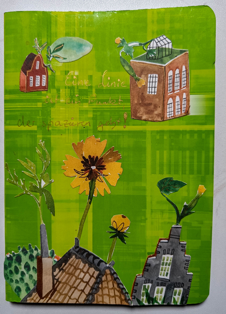 hellgrünes Heft mit Häusercollage wo Blumen aus dem Kamin wachsen