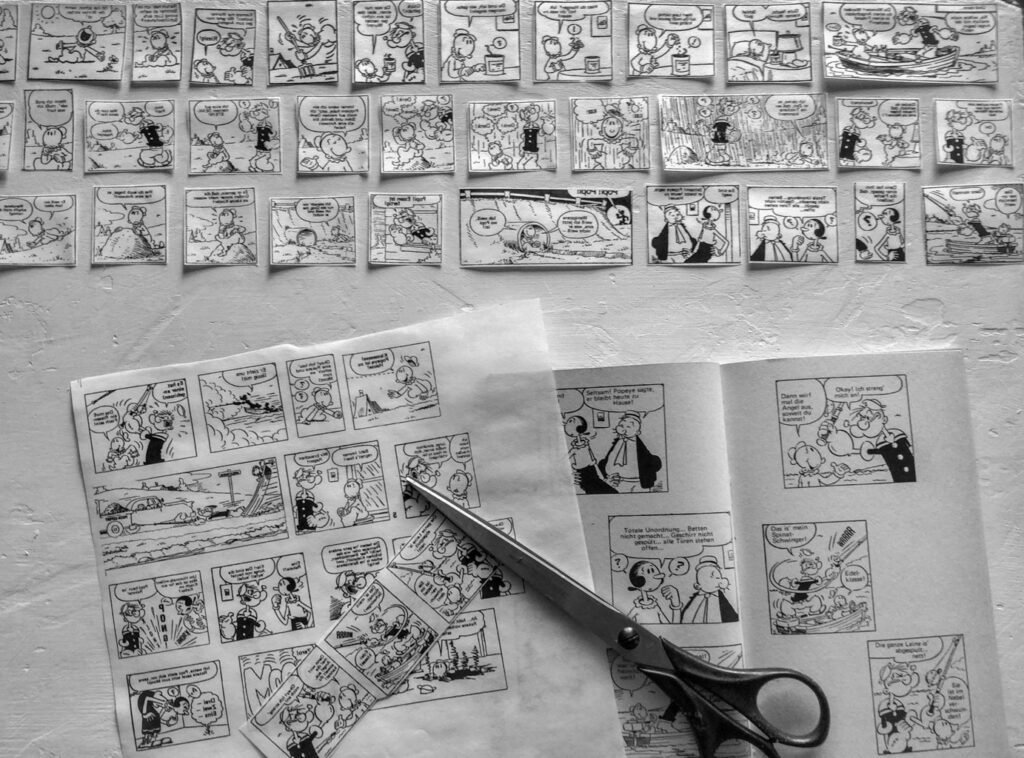 ausgedruckte Popeye-Comicteile in schwarzweiß auf Tischfläche