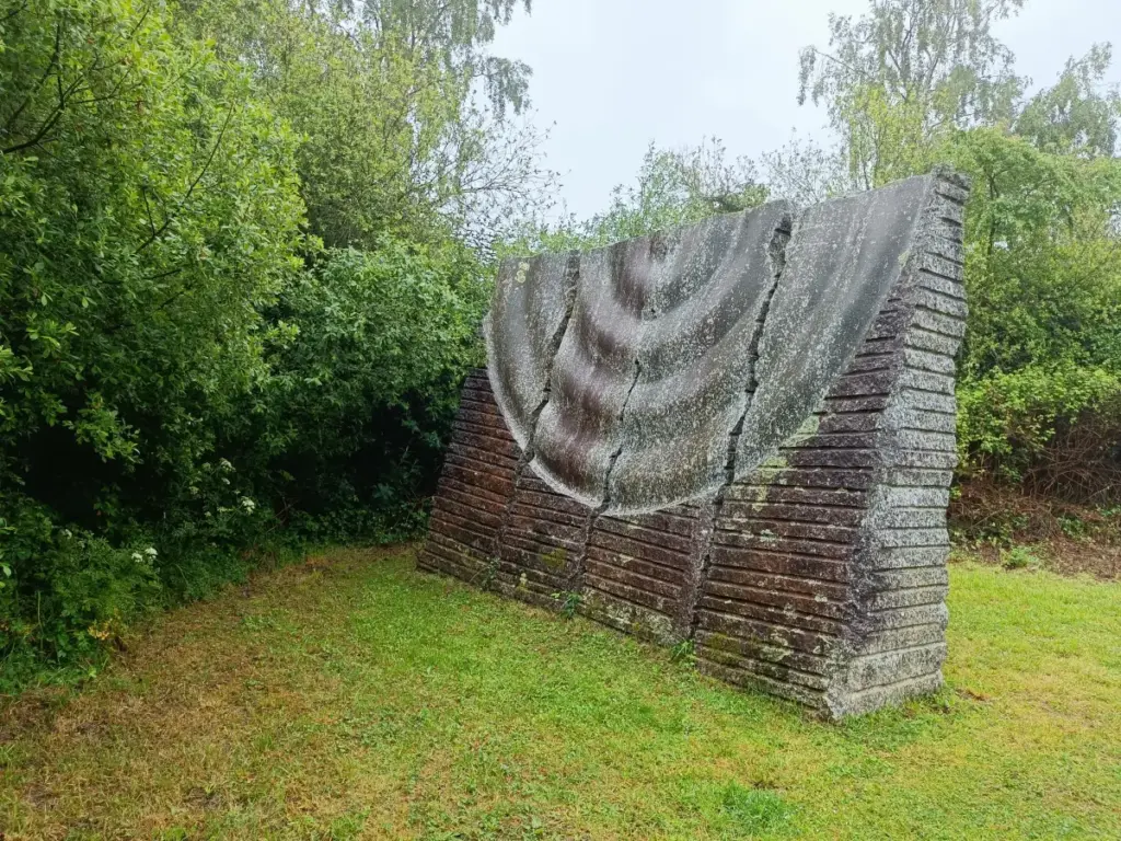 Rückseite Skulptur, die den Wasserlauf darstellen soll, Rillen und oben Wellen, die einen Steinwurf auslösen