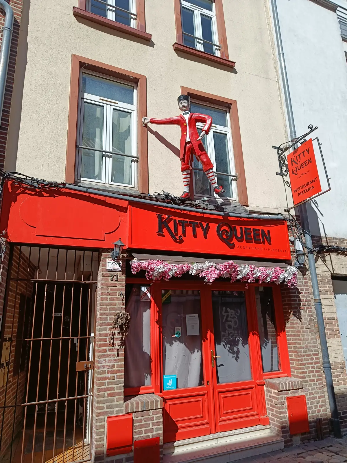 Laden in Amiens mit roten Türen und einer Figur darüber