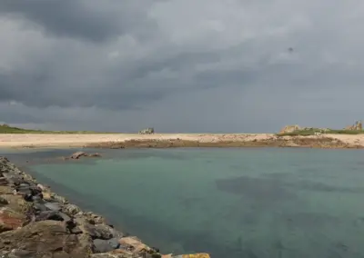 Bucht neben der Mole in Le Diben mit dramatischem Himmel und blauem Wasser
