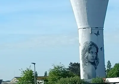 Graffiti von Frauenkopf mit langem welligen Haar und nackter Schulter in schwarzweiß auf Wasserturm bei Morlaix in der Bretagne