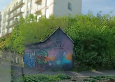 aus dem Auto ein Graffiti von einem kleinen Häuschen für Elektrik mit Blumenmotiven in Morlaix fotografiert