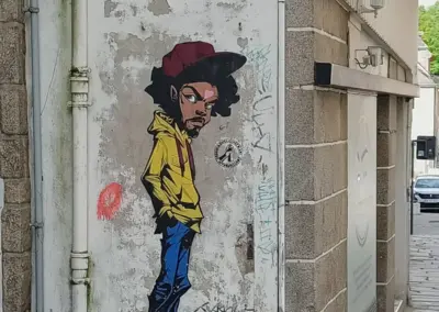 Graffity von männlicher Figur, sehr schmal mit gelbem Oberteil und blauer Hose. Cappy in rostrot mit schwarzen Haaren in Saint Brieuc, Bretagne