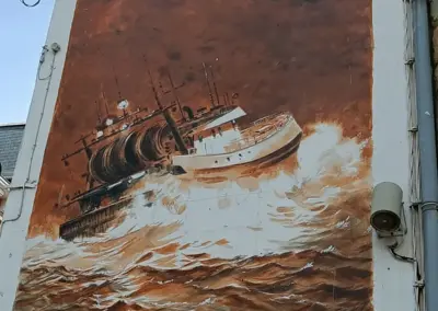 Graffity in weiß-braun Farben mit Schiff in Brandung in Irland, gesehen Saint Brieuc