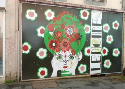 Plakatwand mit Bild von einem Frauenkopf mit Blumenbouque in grün, rostrot. Gesehen in Saint Brieuc, Bretagne